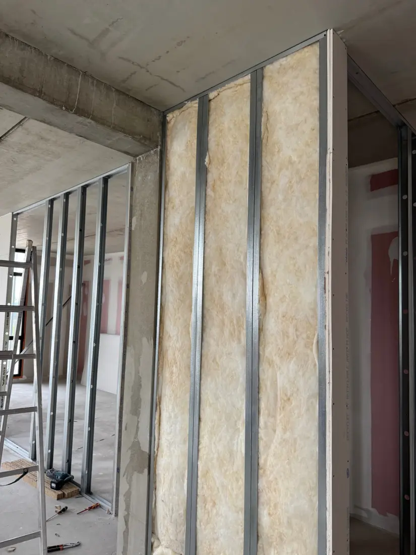 Laine isolante placée entre les montants de la cloison en cours de construction
