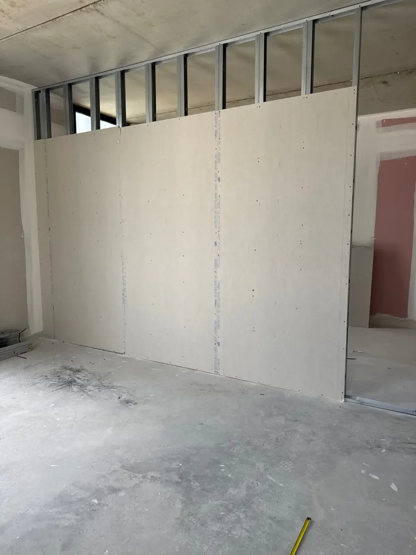 Plaques de plâtre fixées sur la cloison avec montants encore visibles en partie haute
